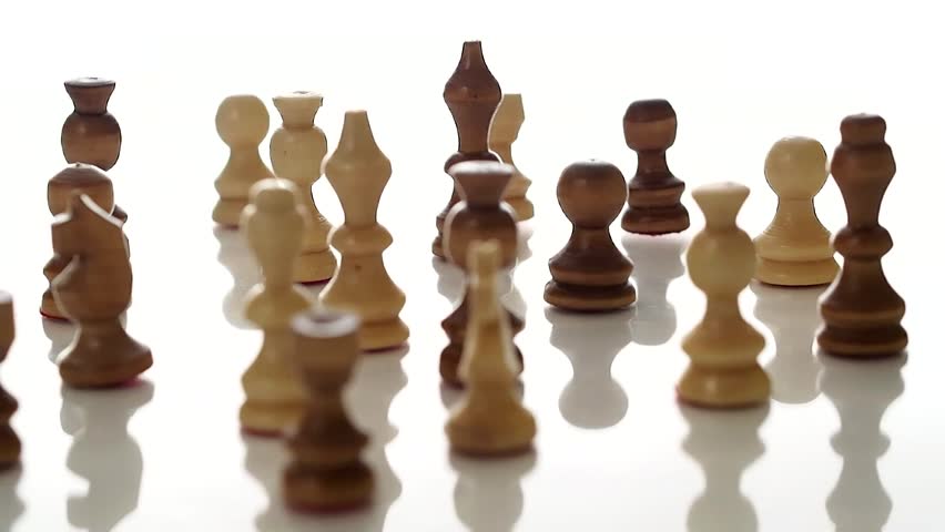 Wooden chess pieces rotating on a white studio background.