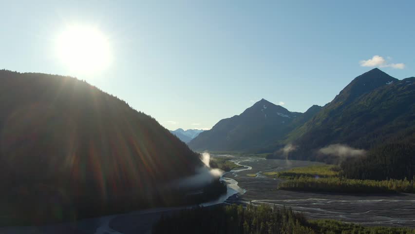 A slowly horizontal moving aerial view of Exit Glacier in Kenai Fjords National Park during fall, featuring a river, the majestic mountains, and the glacier itself. Captured near Seward, Alaska
