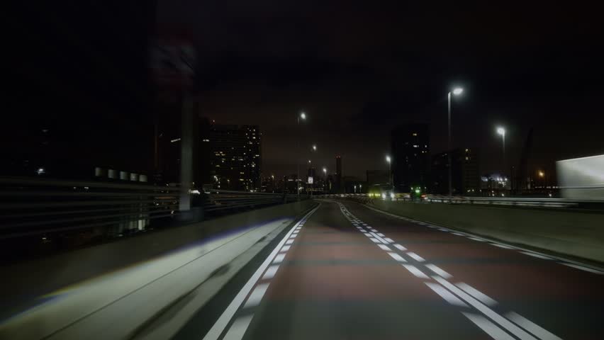 Nighttime Highway in Tokyo’s Expanding Cityscape A view from the car as it cruises Tokyo’s new territories at night, where urban lights and winding roads meet