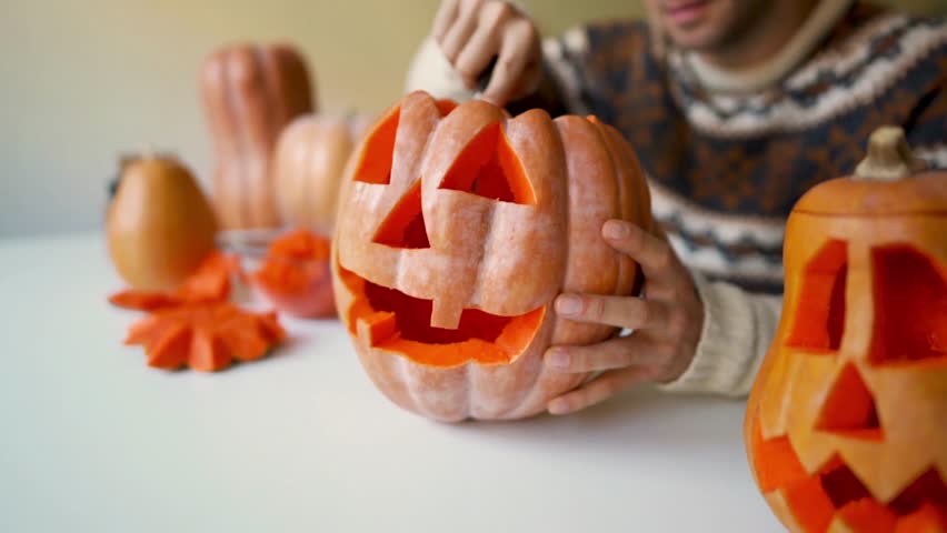 Carving orange pumpkin. Hands carve scary halloween pumpkin. Getting ready for Halloween Cutting Into the Pumpkin
