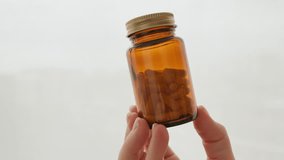Self-care brown glass bottle filled with pills woman hand holding, healthcare, supplements, wellness. Minimalist background emphasizes focus on health products medication management. Lifestyle - Powered by Shutterstock - Get 15% off with code: PIKWIZARD15