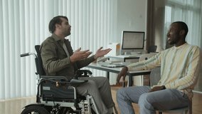 Medium long shot of young Caucasian employee with disability shaking hands with male African American colleague while meeting at office - Powered by Shutterstock - Get 15% off with code: PIKWIZARD15