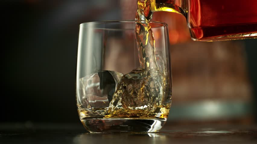 Super Slow Motion of Pouring Whiskey into Glass. Filmed on High Speed Cinema Camera, 1000 fps. Camera placed on Motion Control. Bar on Background, Low Depth of Focus.