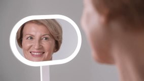 Middle-aged beautiful woman takes a moment to examine her skin closely. The beauty of aging and the journey of selflove - Powered by Shutterstock - Get 15% off with code: PIKWIZARD15