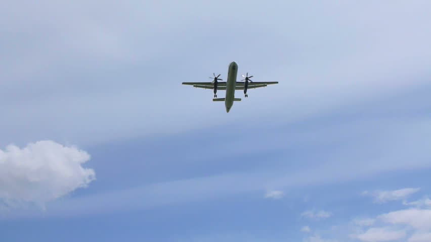 Commercial passenger airplane flying overhead on sunny day.