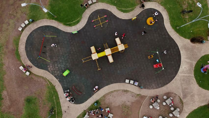 Children play on playground in a park. Static overhead shot