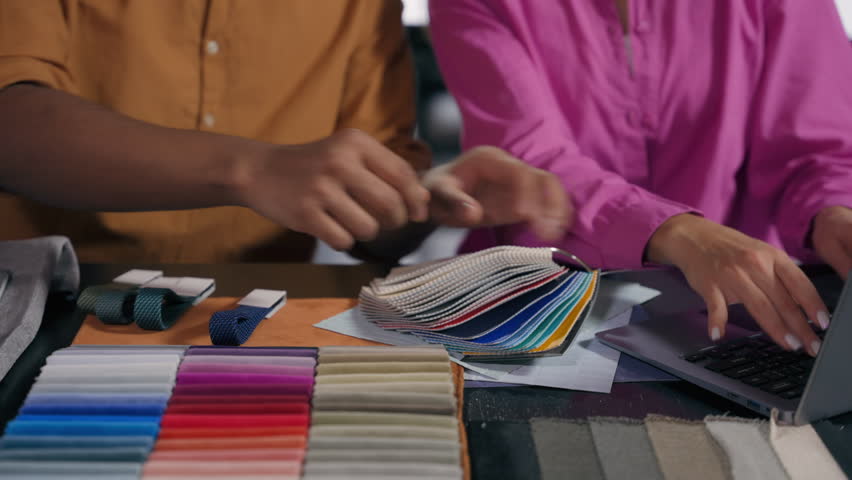 Unrecognizable girl guy fashion designers man woman male tailor female dressmaker at desk new clothes collection colorful cloth catalog fabric samples choose color material order textile online laptop