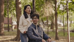 Young woman pushing her boyfriend in a wheelchair in a park - Powered by Shutterstock - Get 15% off with code: PIKWIZARD15
