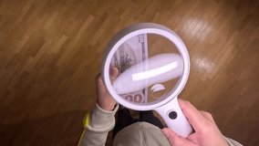 pov First person view man examining one hundred dollar bill magnifying glass - Powered by Shutterstock - Get 15% off with code: PIKWIZARD15