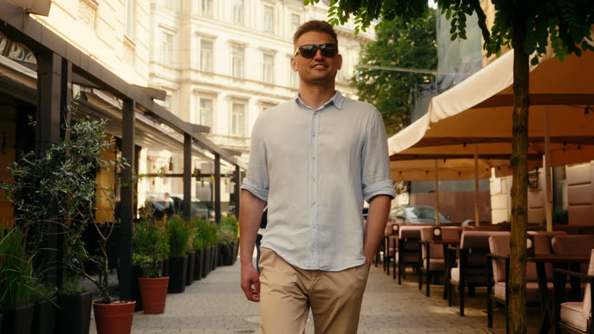Caucasian confident man businessman stylish guy rich traveler happy smiling male going street city cafes walking in fashion sunglasses tourist explore town summer holiday vacation travel insurance