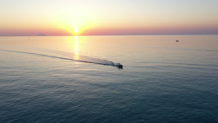 Aerial view of a boat in the sea at sunset on a summer evening