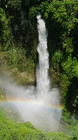 Top view rainbow over Hikong Bente Waterfall surrounded by mountain jungle, rainforest and green trees. Lake Sebu. Mindanao, Philippines. Vertical view.
