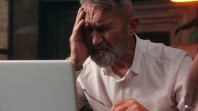 Caucasian old man holding head headache ill unhealthy medicine suffer takes off glasses working laptop businessman business pain computer elderly office male mature technology senior inside migraine - Powered by Shutterstock - Get 15% off with code: PIKWIZARD15