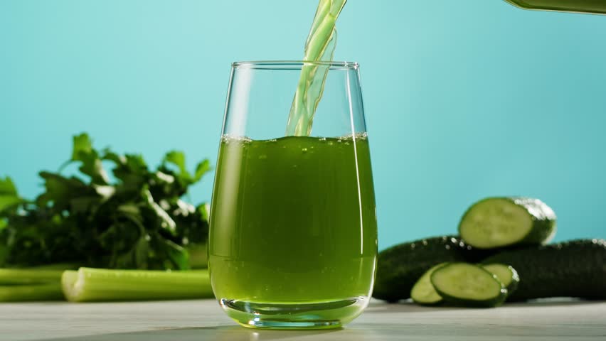 Fresh Green detox juice with cucumber, celery, apple and ginger and mint in glasses and jars. Pouring Vegan juice detox concept.