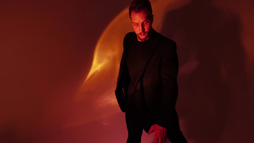 Portrait of a man with a bright orange dynamic light, caustic effect on the face and in space, a guy with a mustache raises his hand