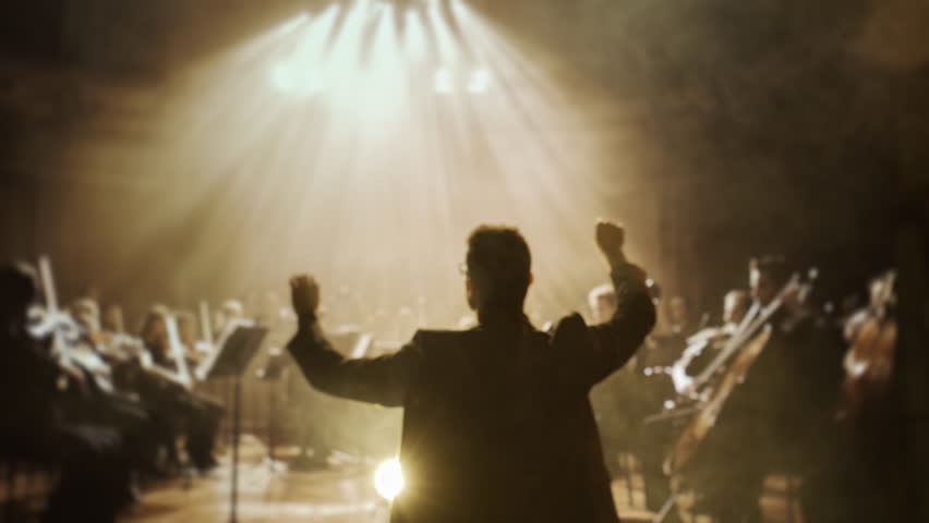 Orchestra Conductor Silhouette Leading Musicians In Concert Hall Dramatic Stage Lighting Performance Art