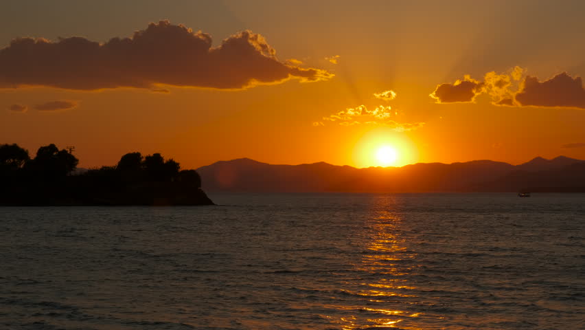 Nightfall towards sea waves. An orange nightfall sky over the calm waves of the bay.