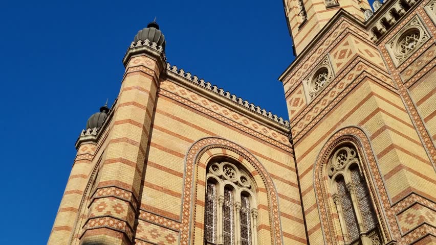 The synagogue in Budapest, Hungary, with a view of the historic old synagogue against a clear blue sky.