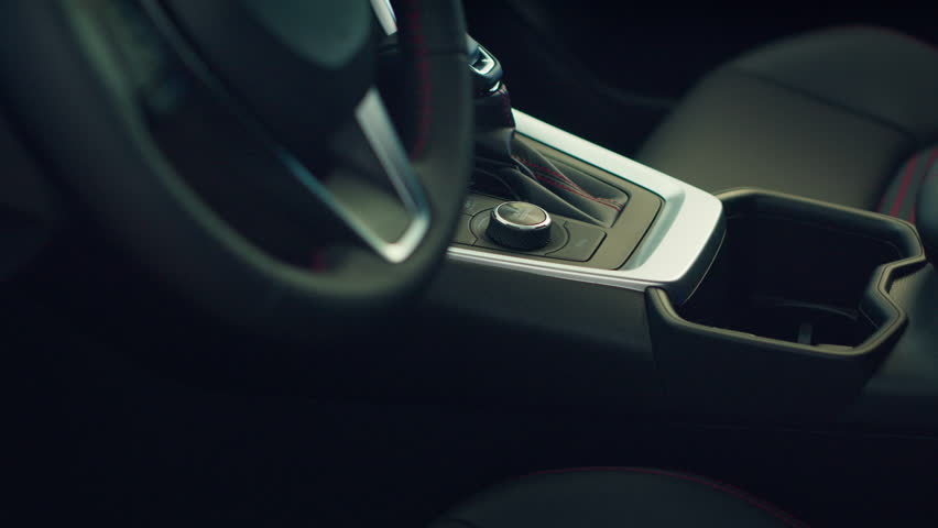 Close up of car interior gearbox gear shift, transmission control panel and buttons activating different vehicle functions. Panning shot of vehicle automatic gearbox control buttons