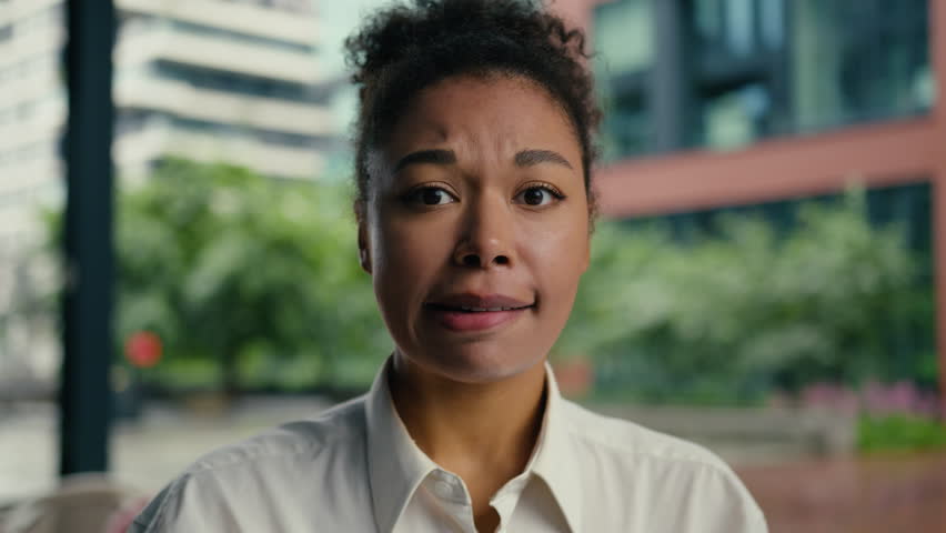 Close up face confused puzzled African American woman girl businesswoman business city bite lip worried thinking uncertainty contemplation choosing doubt hesitate female decision town outdoor employer