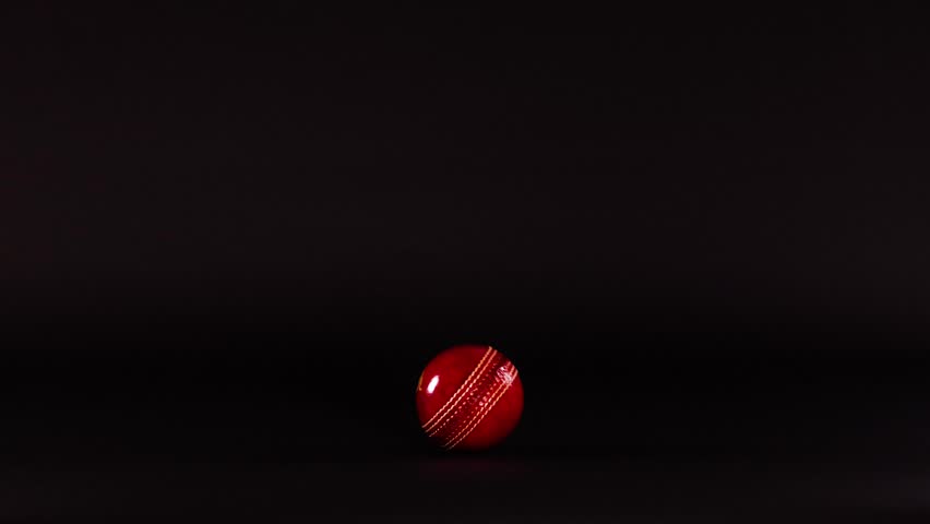A cricket ball moving across a dark background