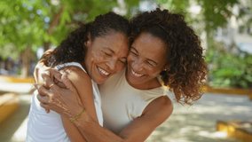 Women sharing a joyful hug outdoors in an urban park, showcasing family love and friendship in a vibrant city setting. - Powered by Shutterstock - Get 15% off with code: PIKWIZARD15