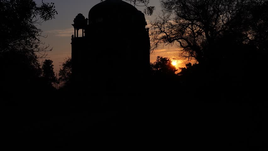 The sun rising in the sky behind the silhouette of Humayun