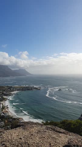 Experience the stunning beauty of Cape Town coastline, where rolling waves meet rugged mountains under a vast sky. This captivating vista showcases nature grandeur at any time of day.