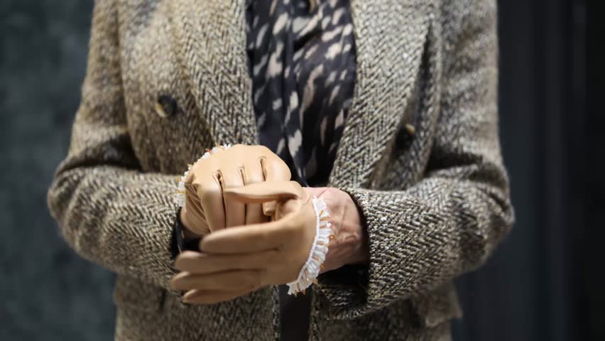 Close-up of woman hands putting on stylish beige leather gloves, luxury Women fashion details, elegance and warmth in cozy, neutral tones for fall and winter