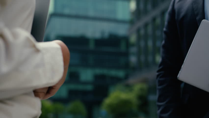 Two multiracial colleagues coworkers business partners Caucasian man businessman guy male African American woman businesswoman female girl in city handshaking shake hands partnership cooperation deal