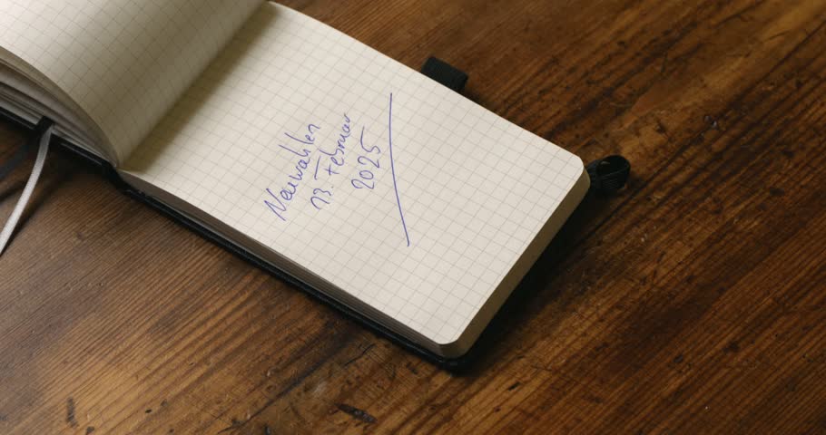 The date of the German new election of the Bundestag and the Chancellor in February 2025 is noted by hand on a paper notebook. 4k video