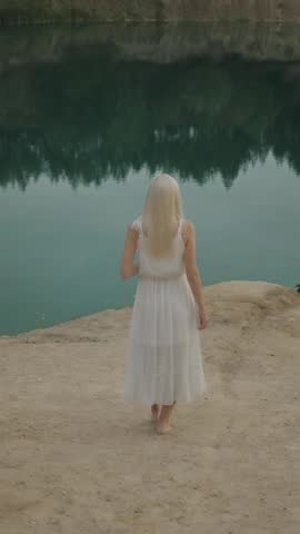 Young blondie woman calling a bird near the lake