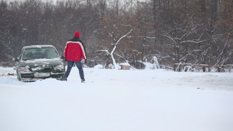 Man and woman tries to release car from snow trap on country road at winter day
