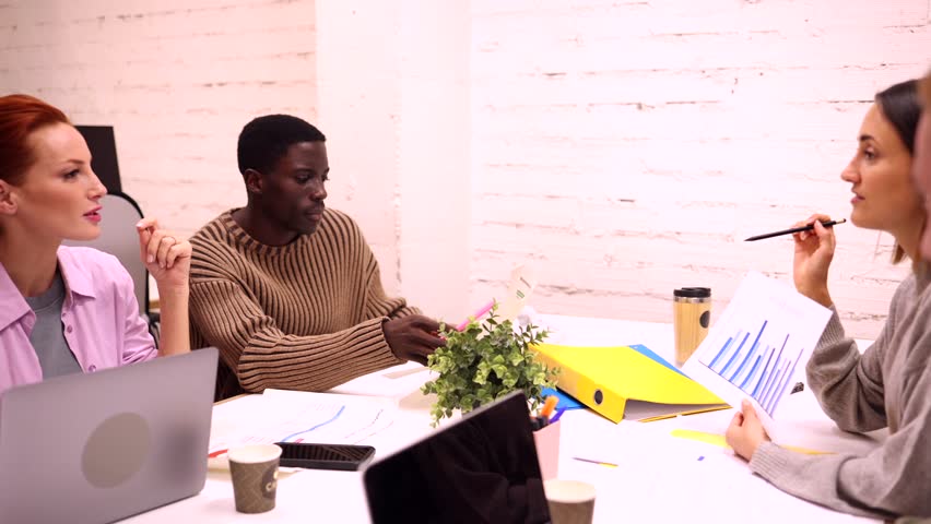 Diverse team of marketing professionals is engaged in a lively discussion, analyzing data and brainstorming ideas to drive growth and achieve their business objectives