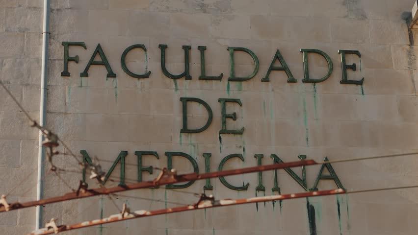 Exterior of Coimbra University’s Faculty of Medicine building with aged lettering