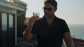 a man in a shirt on the terrace drinking whiskey. Degustation, tasting. Man with beard holds glass of brandy. Tasting and degustation concept. Bearded businessman in elegant suit with glass of whiskey - Powered by Shutterstock - Get 15% off with code: PIKWIZARD15