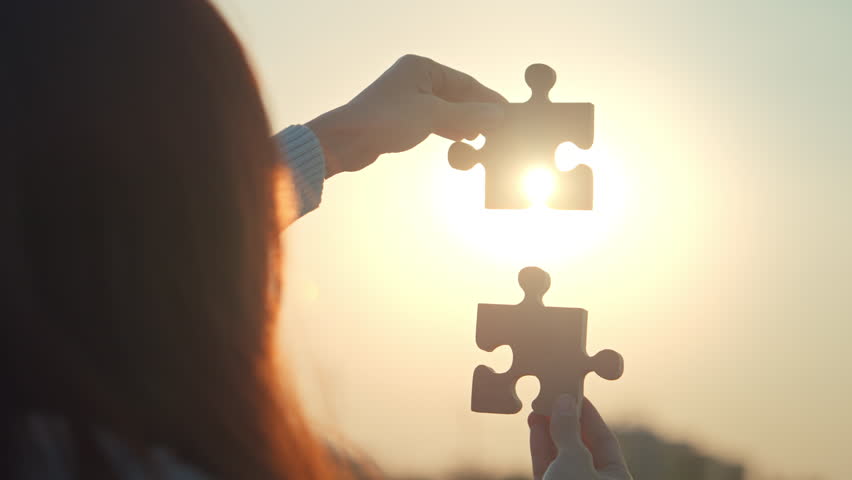 Closeup hands of woman connecting jigsaw puzzle with sunlight effect, Jigsaw alone wooden puzzle against sunset, Business solutions, Success and strategy concept
