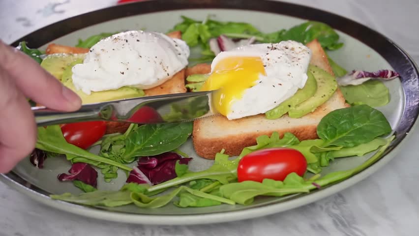 Poached eggs on toast with avocado and fresh salad greens for a breakfast