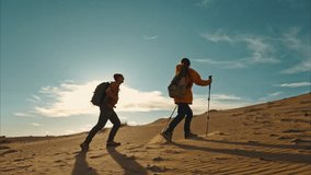 Couple of active hikers walks with hiking poles and backpacks at sunset desert dunes against blue sky - Powered by Shutterstock - Get 15% off with code: PIKWIZARD15