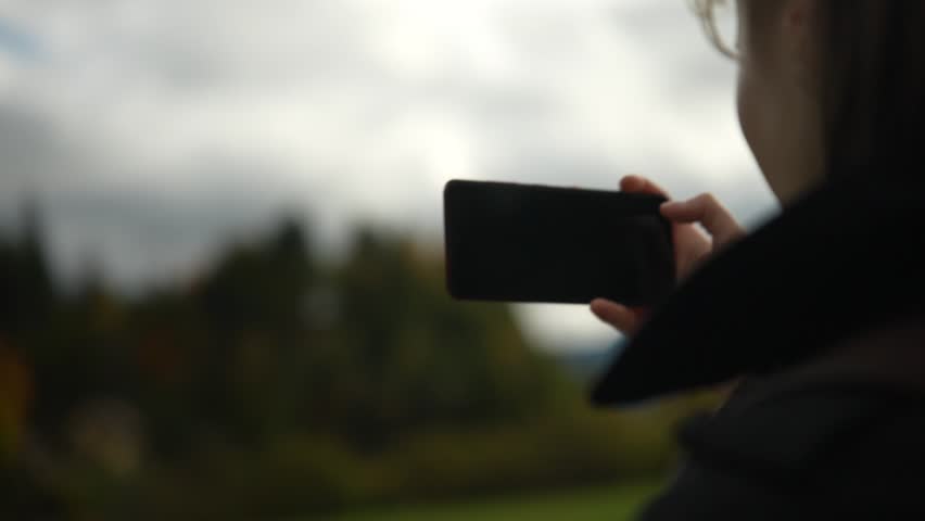  A young girl pictures of attractions on a smartphone in slow motion.