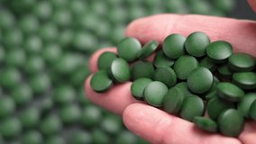 Close-up view of falling spirulina pills from hand. Deep green color and round shape. Ideal for natural health enthusiasts. Promotes energy and supports immunity. Slow motion - Powered by Shutterstock - Get 15% off with code: PIKWIZARD15