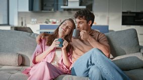 Happy couple drinking coffee together on sofa cozy living room. Relaxed man and woman bonding at peaceful home morning. Joyful spouses talking sitting couch enjoying comfortable domestic atmosphere. - Powered by Shutterstock - Get 15% off with code: PIKWIZARD15