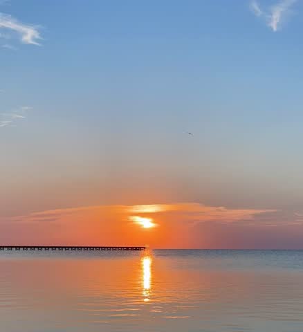 Bay Sunset with a pier in calm water 