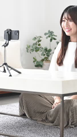 Images taken by video distributors and streamers. Vertical video of a cute young Japanese woman waving and greeting the camera.