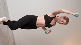 Vertical video. Sports weight. Slimness woman. Smiling trim girl lifting dumbbells at home showcasing strength and dedication to fitness. - Powered by Shutterstock - Get 15% off with code: PIKWIZARD15