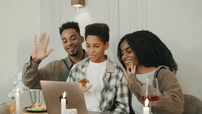 Around a holiday dinner table, an African American family connects with close friends and family through a video call, sharing joy and celebration remotely. - Powered by Shutterstock - Get 15% off with code: PIKWIZARD15
