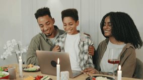 Around a holiday dinner table, an African American family connects with close friends and family through a video call, sharing joy and celebration remotely. - Powered by Shutterstock - Get 15% off with code: PIKWIZARD15