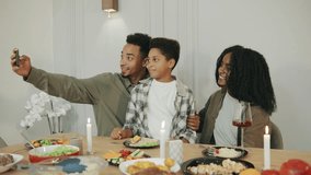An African American family takes a joyful selfie together during their holiday dinner, capturing the festive moments and togetherness around the table. - Powered by Shutterstock - Get 15% off with code: PIKWIZARD15