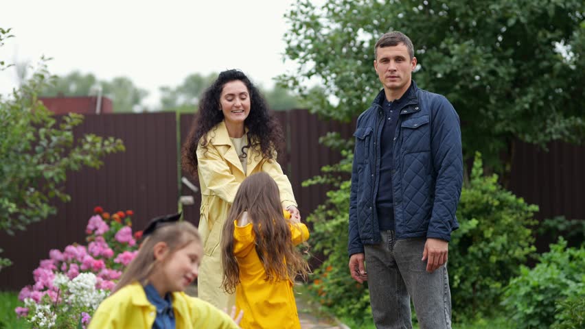 Family is having fun in their garden on a cloudy day, the parents are playing with their daughters