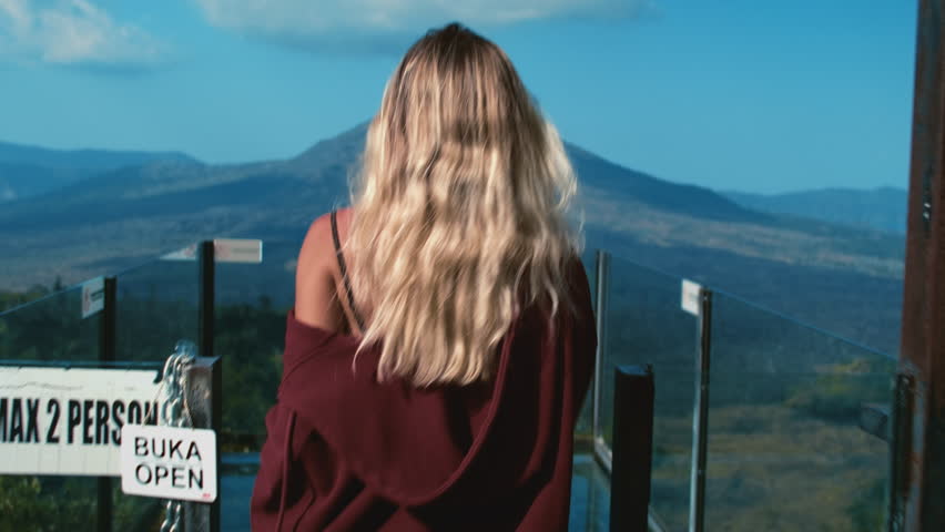 Girls running on the observation deck to watch Batur volcano, Bali Indonesia. A woman looks at the mountain. The female travels through the mountains of Asia, the caldera.